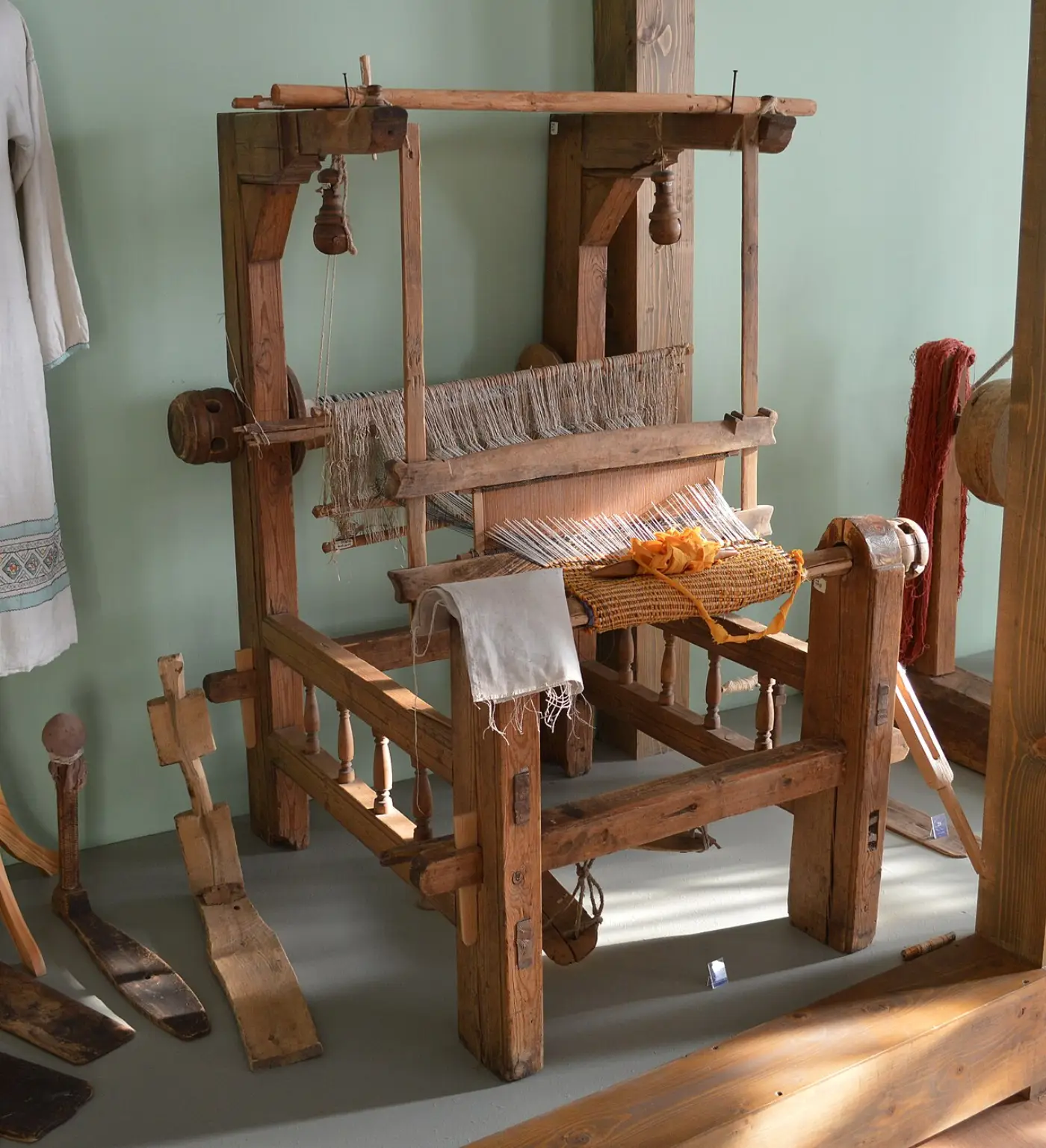 Wooden traditional loom with warp threads, reed and partly woven cloth